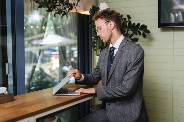 Businessman in suit using laptop in cafe — Stock Photo