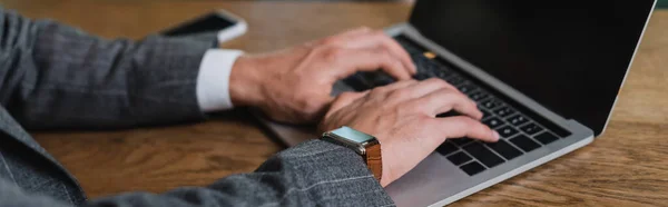 Cropped view of businessman in suit typing on laptop with blank screen in cafe, banner — Stock Photo