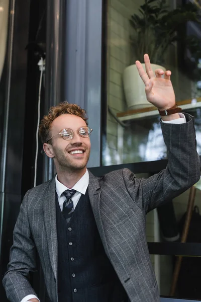 Uomo d'affari felice in occhiali con mano alzata che chiama il cameriere su terrazza di caffè — Foto stock