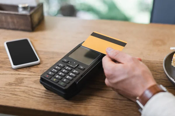 Vista recortada del cliente que paga con tarjeta de crédito en la cafetería - foto de stock