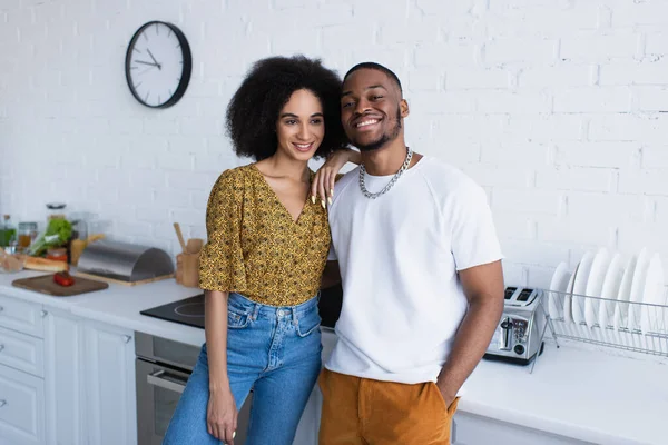 Afroamerikanerin umarmt Freund in Küche — Stockfoto