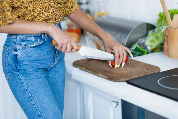 Cropped view of african american woman cutting cherry tomatoes in kitchen — Stock Photo