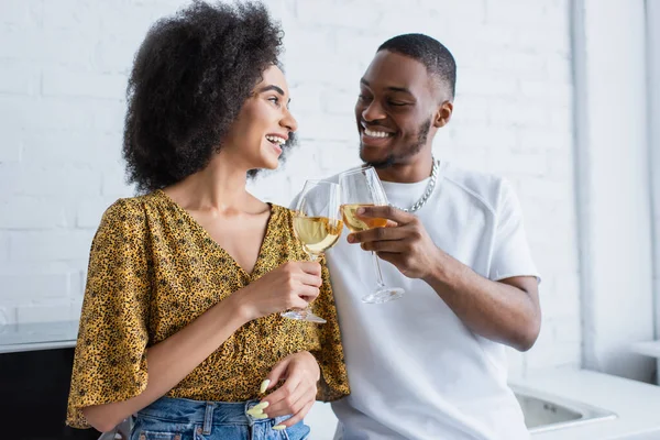 Allegra coppia afro-americana che brinda con vino in cucina — Foto stock