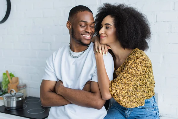Jovem afro-americana abraçando namorado sorridente em casa — Fotografia de Stock