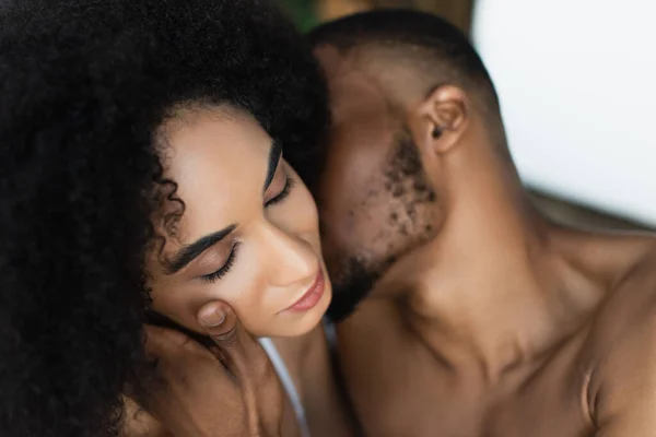 Blurred africano americano hombre tocando sensual mujer en casa - foto de stock