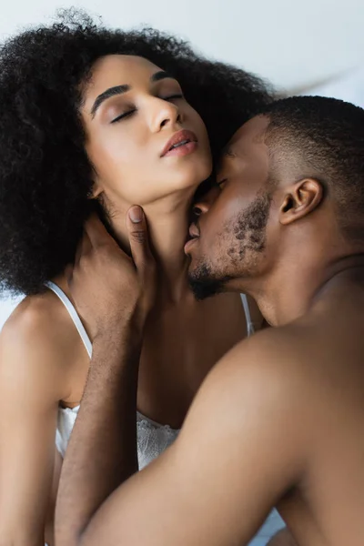 Sensual afroamericano hombre besando bonita novia en sujetador - foto de stock