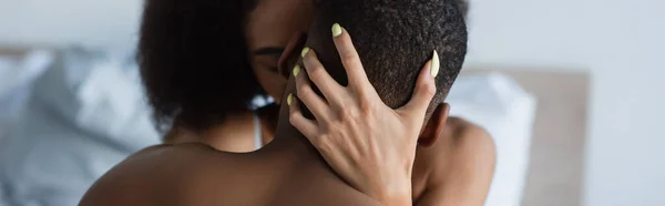 Young african american woman kissing shirtless boyfriend on bedroom, banner — Stock Photo