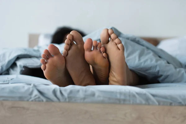 Füße von verschwommenem afrikanisch-amerikanischem Paar auf dem Bett — Stockfoto