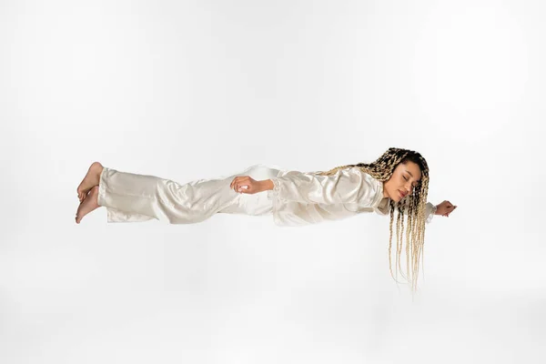 Африканська американка в шовковій піжамі летить уві сні ізольовано на білому — стокове фото