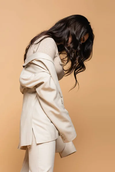 Brunetta giovane modella in dolcevita e blazer posa isolata sul beige — Foto stock