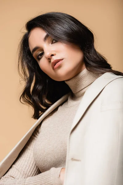 Young pretty model in turtleneck and blazer looking at camera isolated on beige — Stock Photo