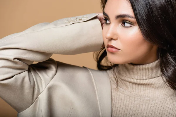 Pretty model in turtleneck and blazer looking away isolated on beige — Stock Photo