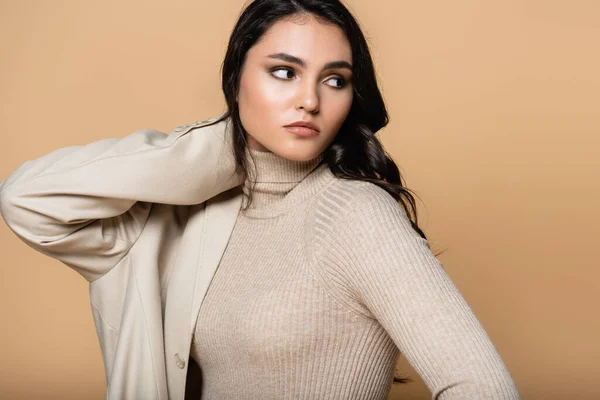 Jeune femme en blazer et col roulé regardant loin isolé sur beige — Photo de stock