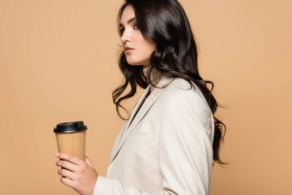 Bonita mujer en cuello alto sosteniendo taza de papel aislado en beige - foto de stock