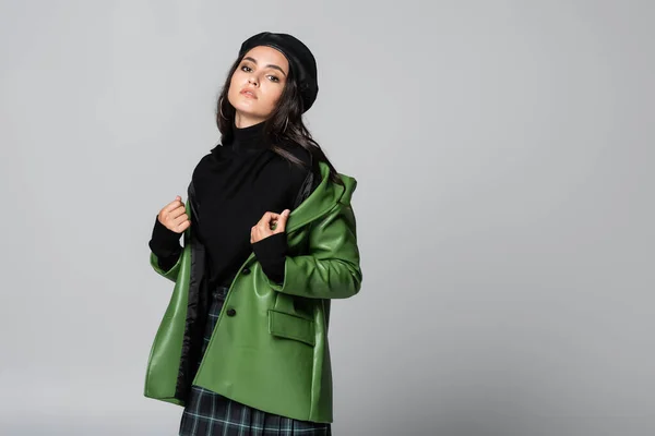 Trendfrau in Baskenmütze trägt grüne Lederjacke isoliert auf grau — Stockfoto
