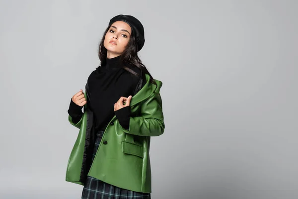 Trendy woman in beret wearing green leather jacket isolated on grey — Stock Photo