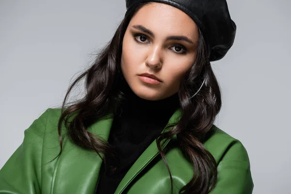 Young woman in black turtleneck, green jacket and beret looking at camera isolated on grey — Stock Photo