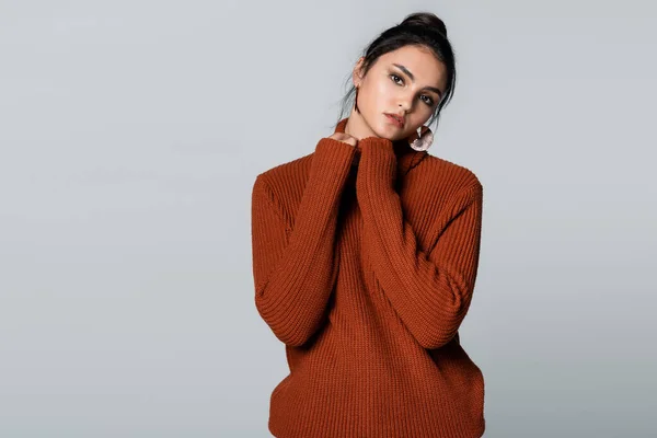 Young woman in warm sweater looking at camera isolated on grey — Stock Photo