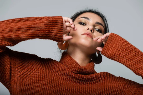 Young woman in knitted sweater looking at camera and posing isolated on grey — Stock Photo