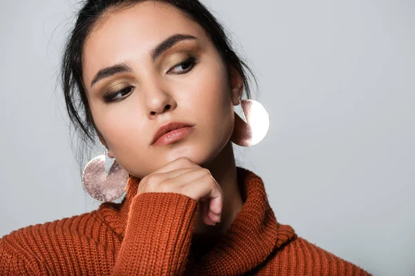 Giovane donna in maglione caldo e orecchini guardando altrove isolato su grigio — Foto stock