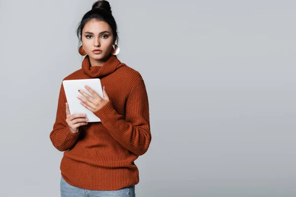 Junge Frau im Strickpullover hält digitales Tablet isoliert auf grau — Stockfoto