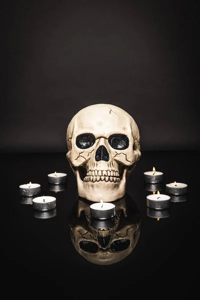 Burning candles near spooky skull on black — Stock Photo