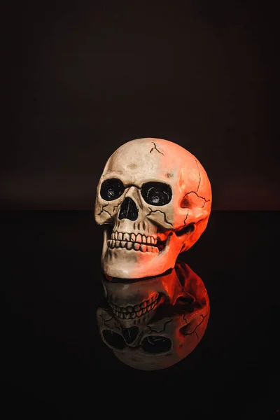 Red lighting on aged and creepy skull on black — Stock Photo