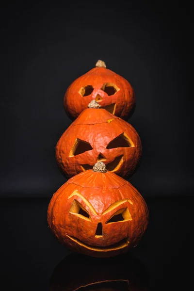 Row of creepy and carved pumpkins on black — Stock Photo