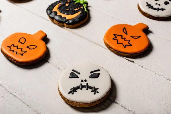 Primer plano de galletas de jengibre dulces y espeluznantes en la superficie blanca - foto de stock