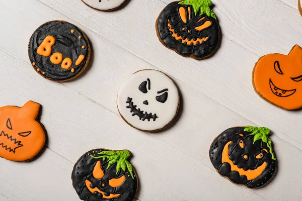 Vista dall'alto di dolci e inquietanti biscotti di Halloween a forma di zucca sulla superficie bianca — Foto stock