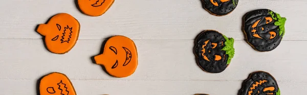 Top view of sweet and spooky pumpkin shape halloween cookies on white surface, banner — Stock Photo