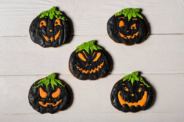 Flay lay with black and spooky pumpkin shape halloween cookies on white surface — Stock Photo