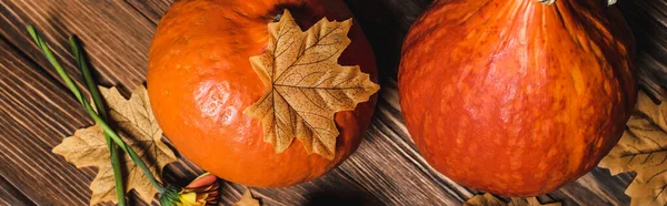 Top view of autumnal leaves near orange pumpkins on wooden surface, banner — Stock Photo