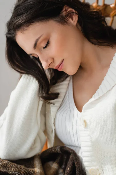 Brunette femme avec les yeux fermés reposant à la maison dans un cardigan chaud — Photo de stock