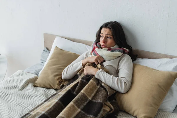 Diseased woman lying in bed under checkered blanket at home — Stock Photo