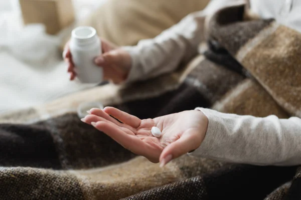 Vue partielle de la femme malade avec pilule sur la paume ouverte, fond flou — Photo de stock