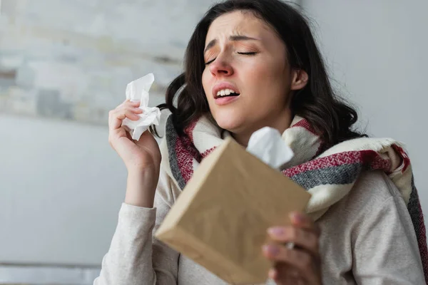 Diseased woman holding paper napkins while sneezing with closed eyes — Stock Photo