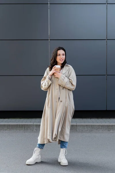 Donna bruna in elegante abito autunnale in piedi con caffè per andare e distogliere lo sguardo — Foto stock