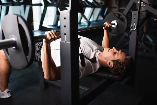 Homme sportif travaillant sur la machine d'exercice d'haltérophilie dans la salle de gym — Photo de stock