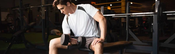 Sportsman exercising with dumbbell while sitting in gym, banner — Stock Photo