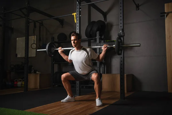 Vue complète de l'homme athlétique faisant de l'exercice avec haltère dans le centre sportif — Photo de stock