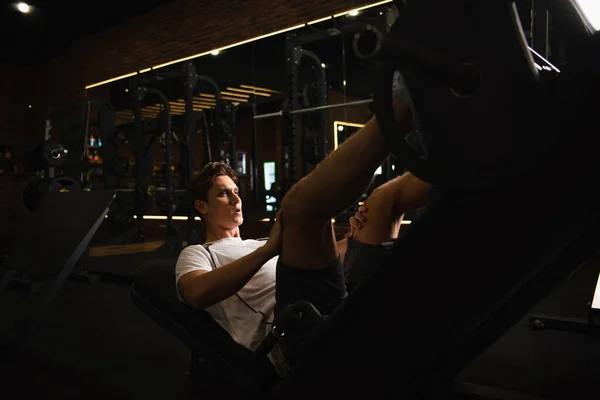 Спортсмен, який працює над розширенням ніг тренувальна машина в спортивному центрі — стокове фото