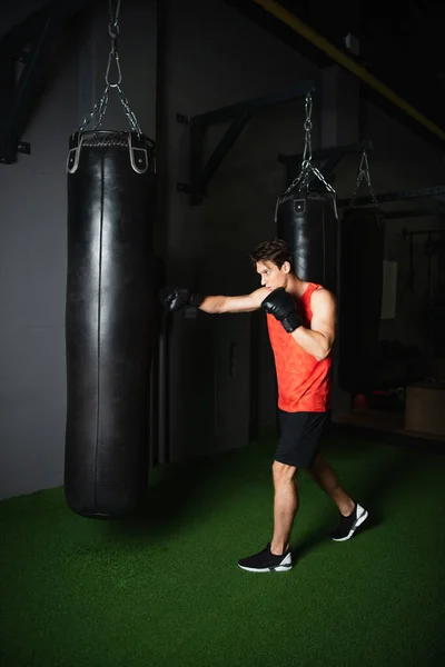 Vue pleine longueur du boxeur travaillant avec un sac de boxe dans le centre sportif — Photo de stock