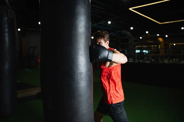Boxer d'entraînement avec sac de boxe dans le centre sportif — Photo de stock