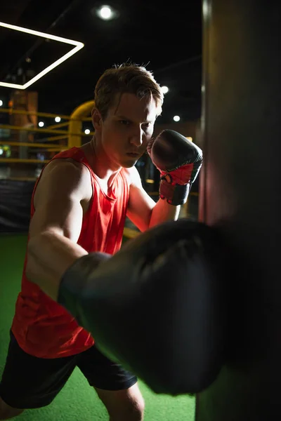 Sportlicher Mann in Boxhandschuhen trainiert mit Boxsack im Fitnessstudio — Stockfoto