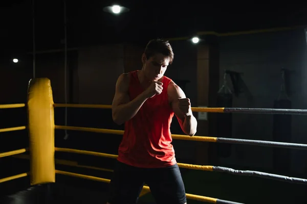 Athletic man boxing in ring while training in sports center — Stock Photo