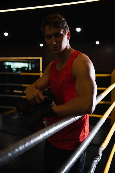 Hombre deportivo mirando hacia otro lado mientras está de pie en el ring de boxeo - foto de stock
