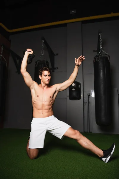 Homme athlétique torse nu en short d'exercice avec kettlebell dans la salle de gym — Photo de stock