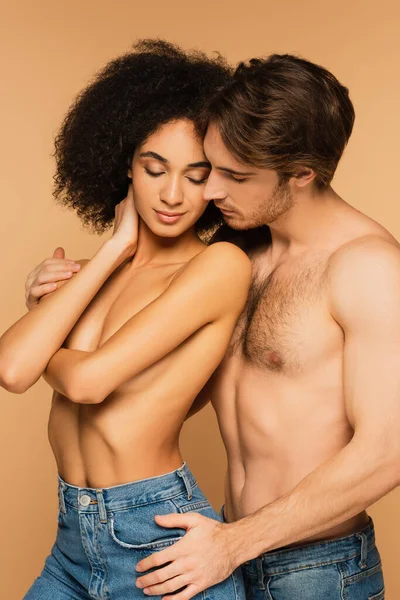 Shirtless man embracing sensual and topless latin woman isolated on beige — Stock Photo