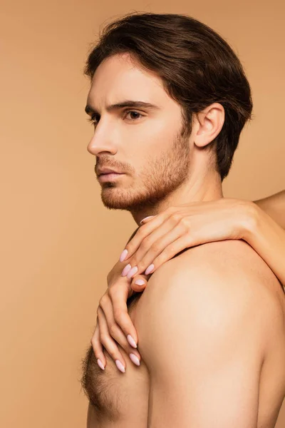 Woman embracing young shirtless lover looking away isolated on beige — Stock Photo